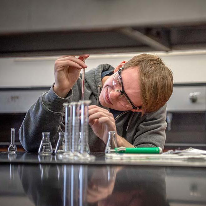 Chemistry student dropping chemicals into beeker